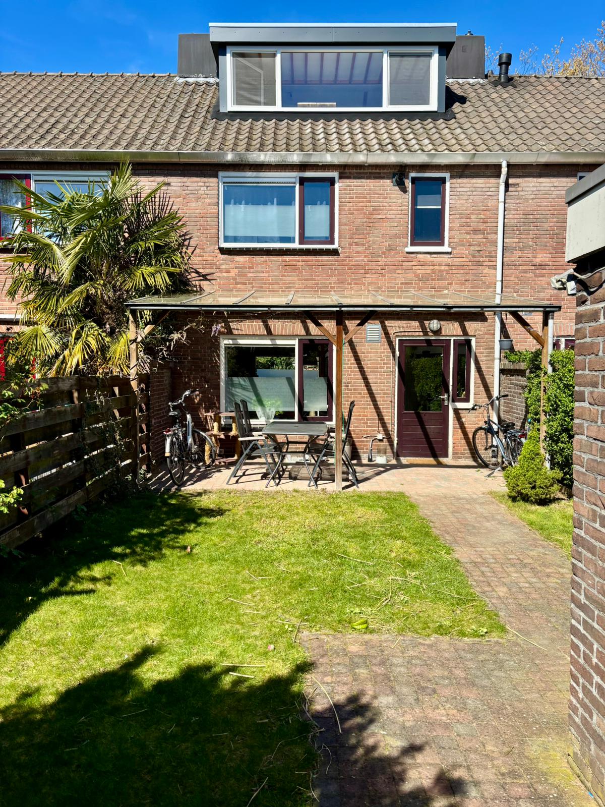 Sunny backyard with seating area and view of the house.